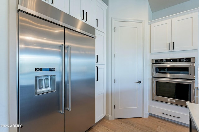 kitchen with white cabinetry, light wood-type flooring, and appliances with stainless steel finishes