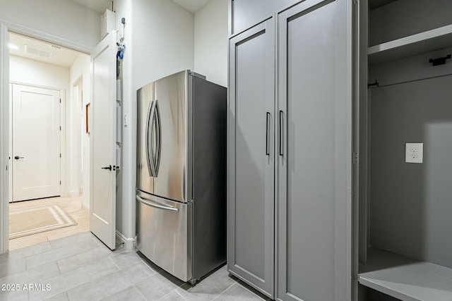 kitchen featuring gray cabinets, stainless steel refrigerator, and light tile patterned flooring