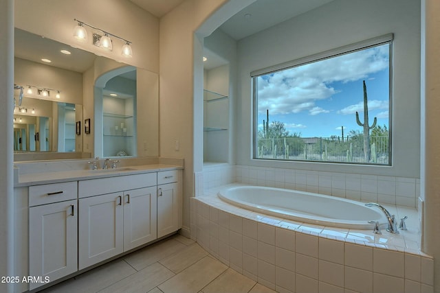 bathroom with tile patterned floors, built in shelves, vanity, and a relaxing tiled tub