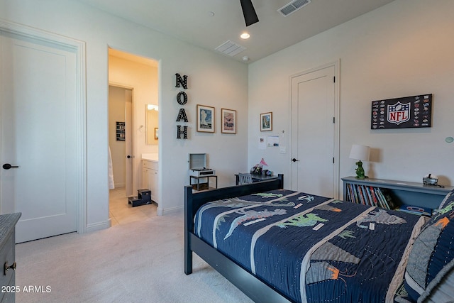 bedroom with ceiling fan, light colored carpet, and ensuite bathroom