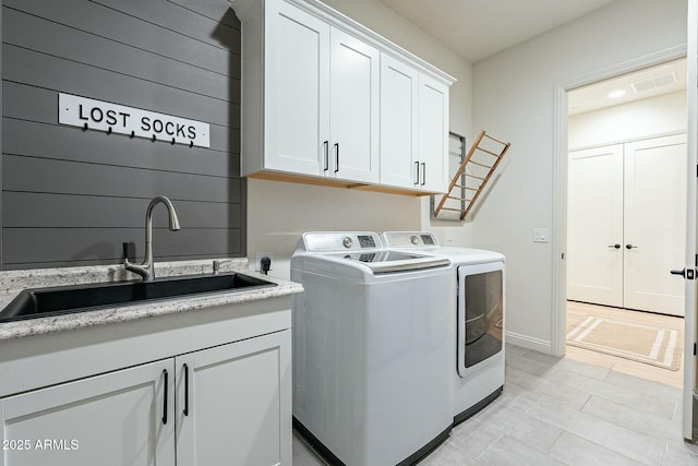 washroom with cabinets, light tile patterned floors, washer and clothes dryer, and sink