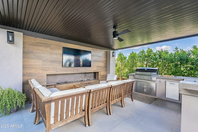 view of patio featuring an outdoor living space with a fireplace, grilling area, ceiling fan, and exterior kitchen