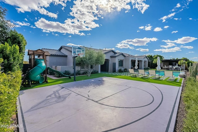 view of sport court with a lawn and a playground