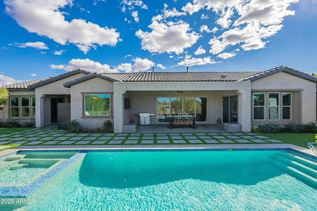 rear view of house featuring a swimming pool with hot tub and a patio