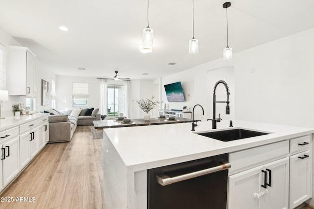 kitchen with sink, dishwasher, white cabinetry, hanging light fixtures, and an island with sink