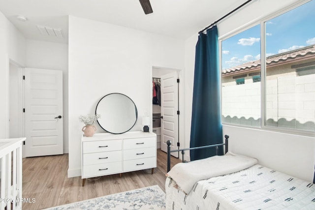 bedroom featuring multiple windows, a spacious closet, light hardwood / wood-style floors, and a closet