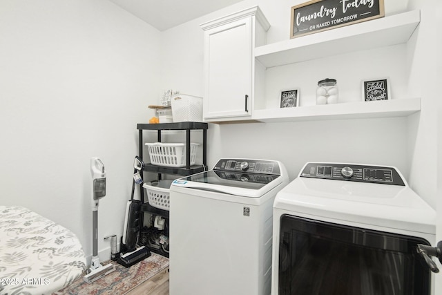 laundry room featuring hardwood / wood-style flooring, washing machine and dryer, and cabinets