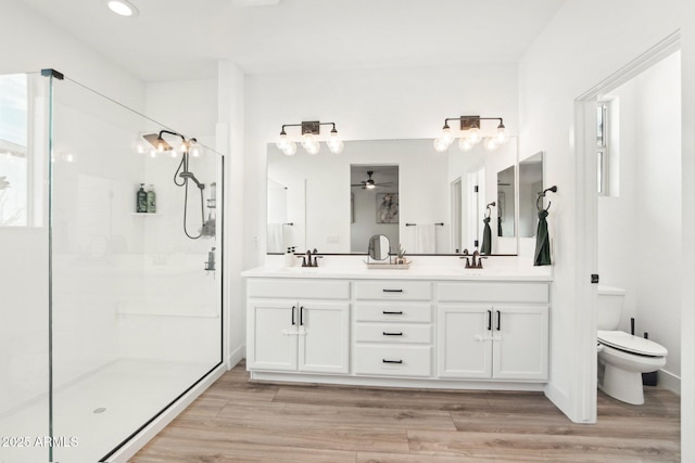 bathroom with ceiling fan, hardwood / wood-style floors, vanity, an enclosed shower, and toilet