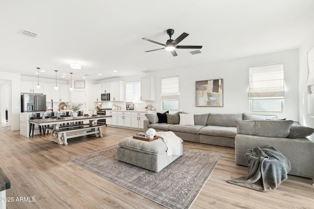 living room with ceiling fan and light wood-type flooring