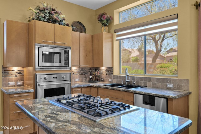 kitchen featuring decorative backsplash, appliances with stainless steel finishes, dark stone counters, and plenty of natural light