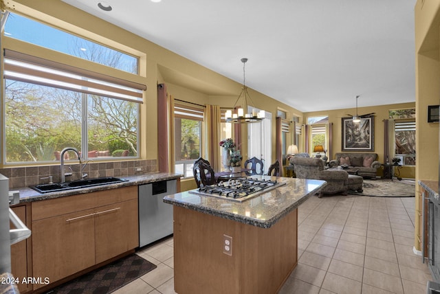 kitchen with sink, appliances with stainless steel finishes, dark stone counters, an inviting chandelier, and decorative backsplash