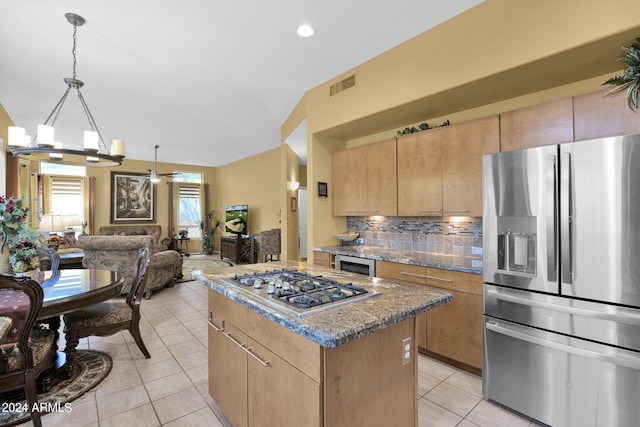 kitchen featuring a kitchen island, backsplash, appliances with stainless steel finishes, light tile patterned floors, and stone counters