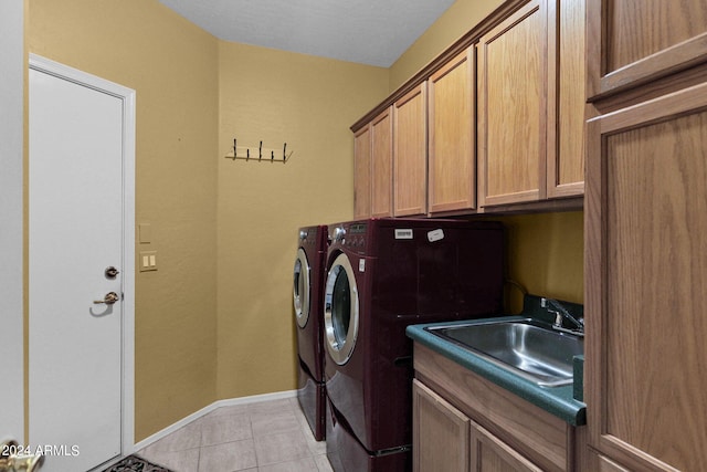 clothes washing area with cabinets, washing machine and dryer, sink, and light tile patterned flooring