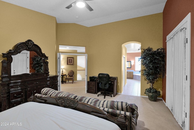 bedroom featuring light carpet, ceiling fan, vaulted ceiling, and connected bathroom