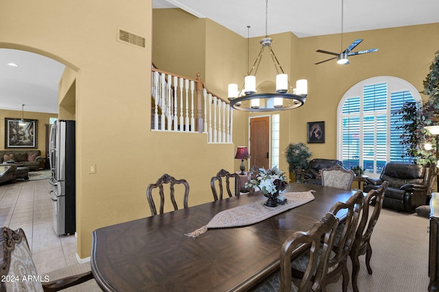 tiled dining area with a high ceiling and ceiling fan with notable chandelier