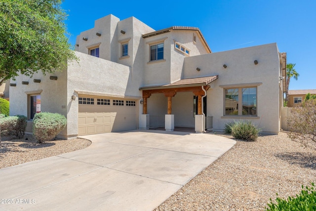 pueblo revival-style home featuring concrete driveway, a garage, and stucco siding