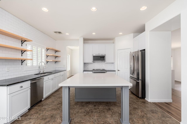 kitchen featuring backsplash, open shelves, white cabinets, appliances with stainless steel finishes, and a sink