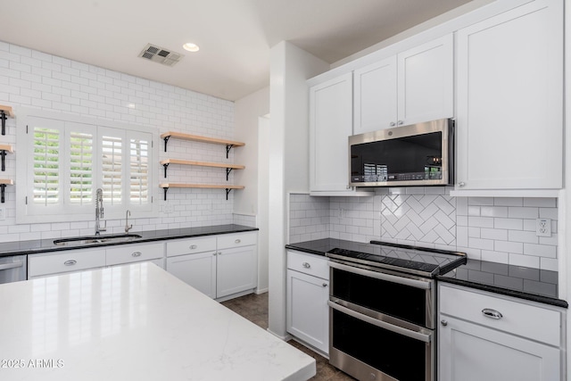 kitchen featuring stainless steel appliances, visible vents, a sink, and decorative backsplash