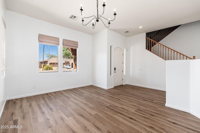 interior space featuring baseboards, a notable chandelier, recessed lighting, wood finished floors, and stairs