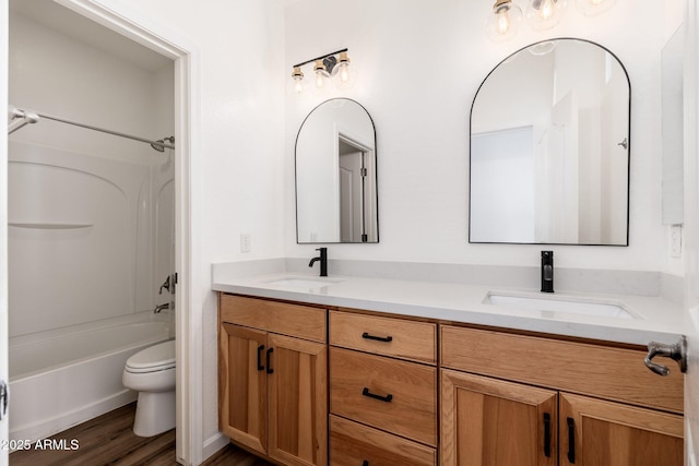 full bath with double vanity, a sink, toilet, and wood finished floors