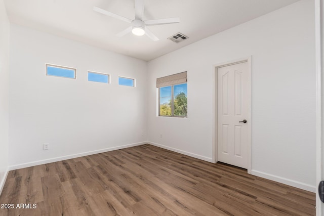 spare room with wood finished floors, baseboards, a ceiling fan, and visible vents