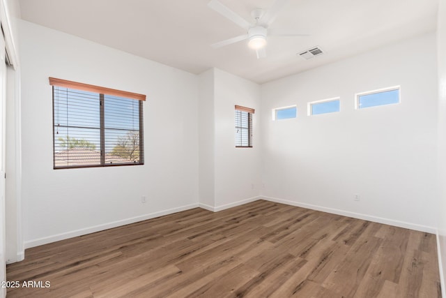 unfurnished room featuring wood finished floors, ceiling fan, baseboards, and visible vents