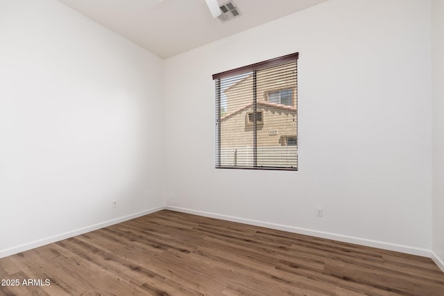 empty room featuring visible vents, baseboards, and wood finished floors