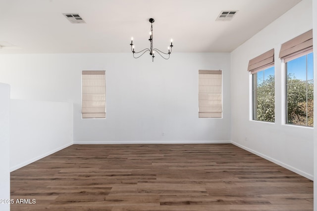 spare room with visible vents, baseboards, an inviting chandelier, and wood finished floors