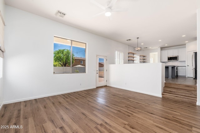 unfurnished living room featuring visible vents, baseboards, a ceiling fan, and wood finished floors