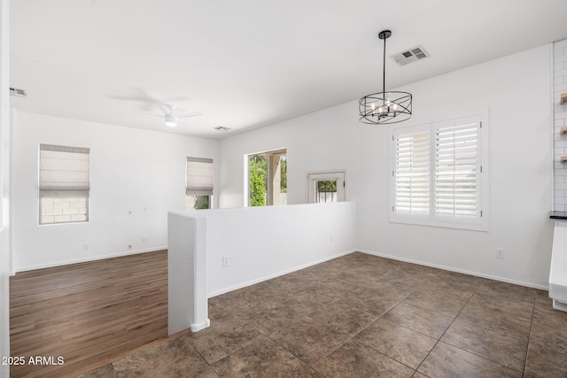 unfurnished room with ceiling fan with notable chandelier, baseboards, and visible vents