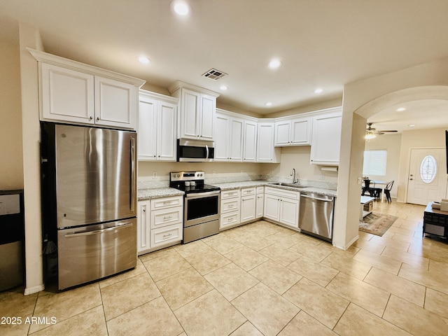 719 S 2nd St, Avondale, AZ 85323 - kitchen with appliances with stainless steel finishes, a ceiling fan, a sink, arched walkways, and white cabinetry