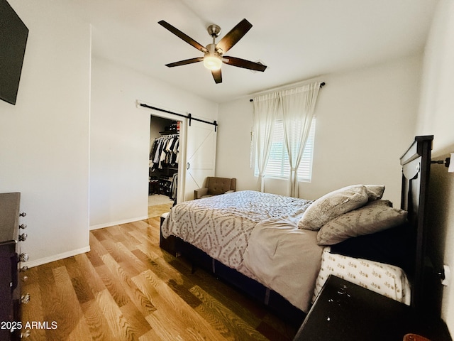 719 S 2nd St, Avondale, AZ 85323 - bedroom with a barn door, wood finished floors, baseboards, ceiling fan, and a spacious closet