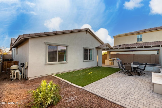 rear view of property with a tiled roof, a patio area, a fenced backyard, and stucco siding