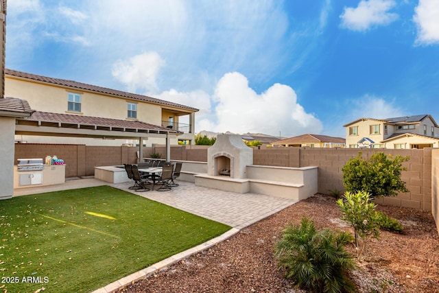 back of property with exterior kitchen, a fenced backyard, a patio, and exterior fireplace