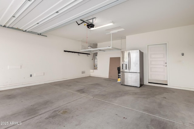 garage featuring baseboards, stainless steel fridge, and a garage door opener