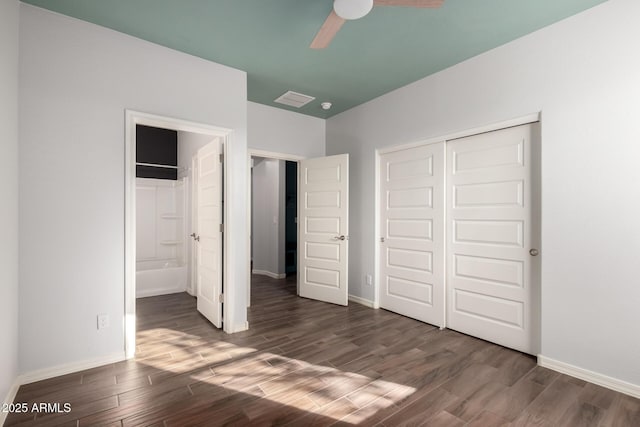 unfurnished bedroom with dark wood-style floors, a closet, visible vents, ensuite bath, and baseboards