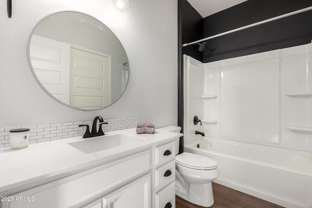 bathroom featuring toilet, shower / bath combination, wood finished floors, vanity, and backsplash