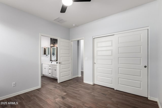 unfurnished bedroom with dark wood-style flooring, a closet, visible vents, and baseboards