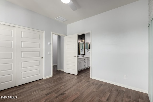 unfurnished bedroom featuring dark wood-style floors, baseboards, visible vents, and a closet