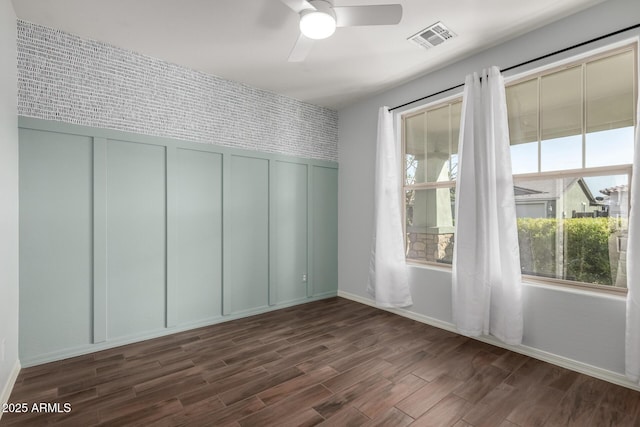 interior space with dark wood-type flooring, visible vents, ceiling fan, and baseboards