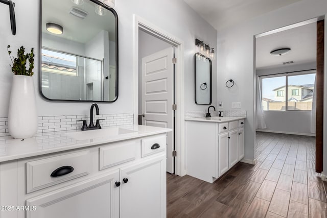 bathroom featuring a healthy amount of sunlight, backsplash, a sink, and wood finished floors