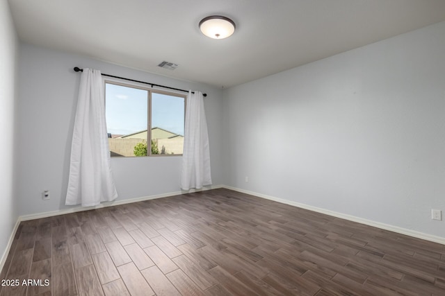 unfurnished room with baseboards, visible vents, and dark wood-type flooring