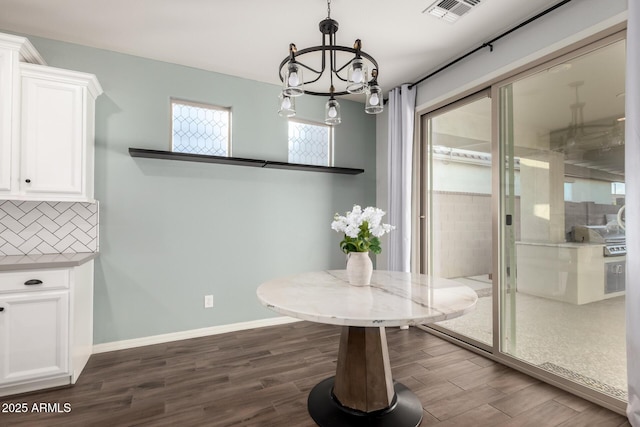 dining space featuring baseboards, visible vents, dark wood finished floors, and a notable chandelier