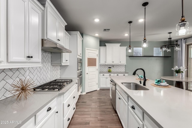 kitchen with stainless steel appliances, light countertops, a sink, and under cabinet range hood