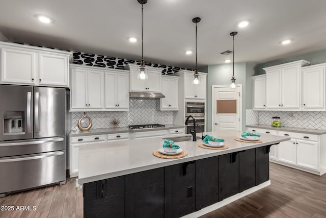 kitchen featuring visible vents, white cabinets, stainless steel appliances, under cabinet range hood, and a sink