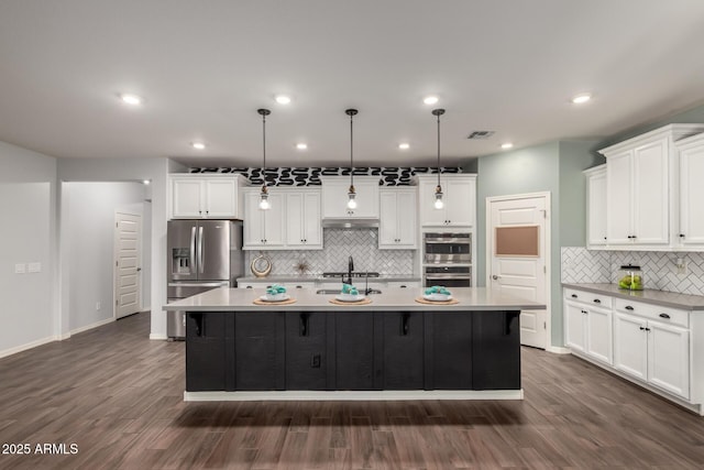 kitchen featuring dark wood finished floors, a large island, stainless steel appliances, light countertops, and white cabinetry