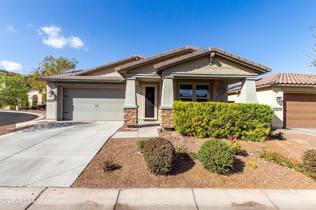 view of front facade with a garage, concrete driveway, stone siding, a tiled roof, and stucco siding