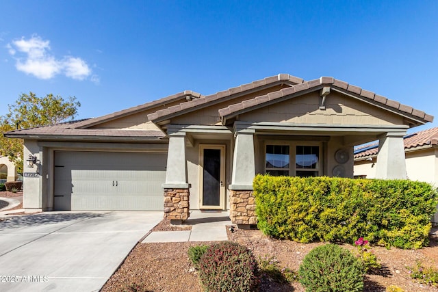 view of front of home with stone siding, an attached garage, a tiled roof, and stucco siding