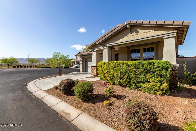 view of front of home with an attached garage, a mountain view, concrete driveway, and stucco siding