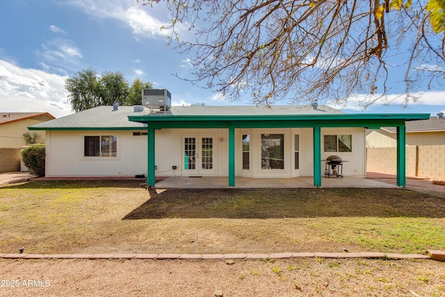 rear view of property with a lawn, a patio, central AC, fence, and french doors